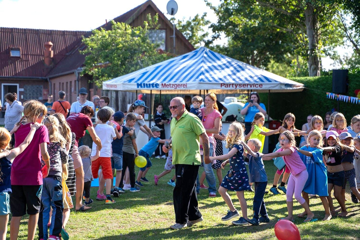 Animator danst met kinderen op het zomerfeest