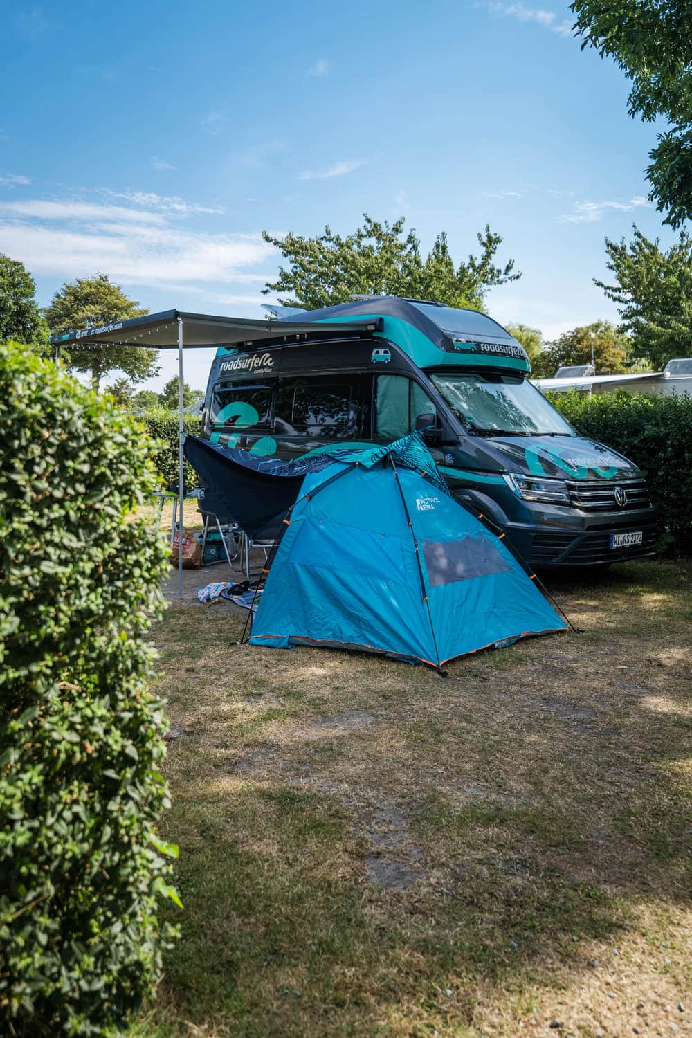 Campingbus mit Vorzelt unter Bäumen