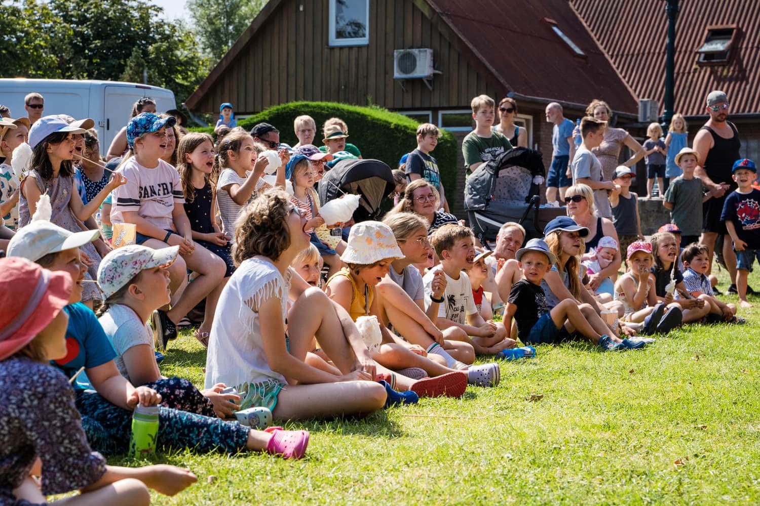 Kinder sitzen auf der Wiese vor der Bühne