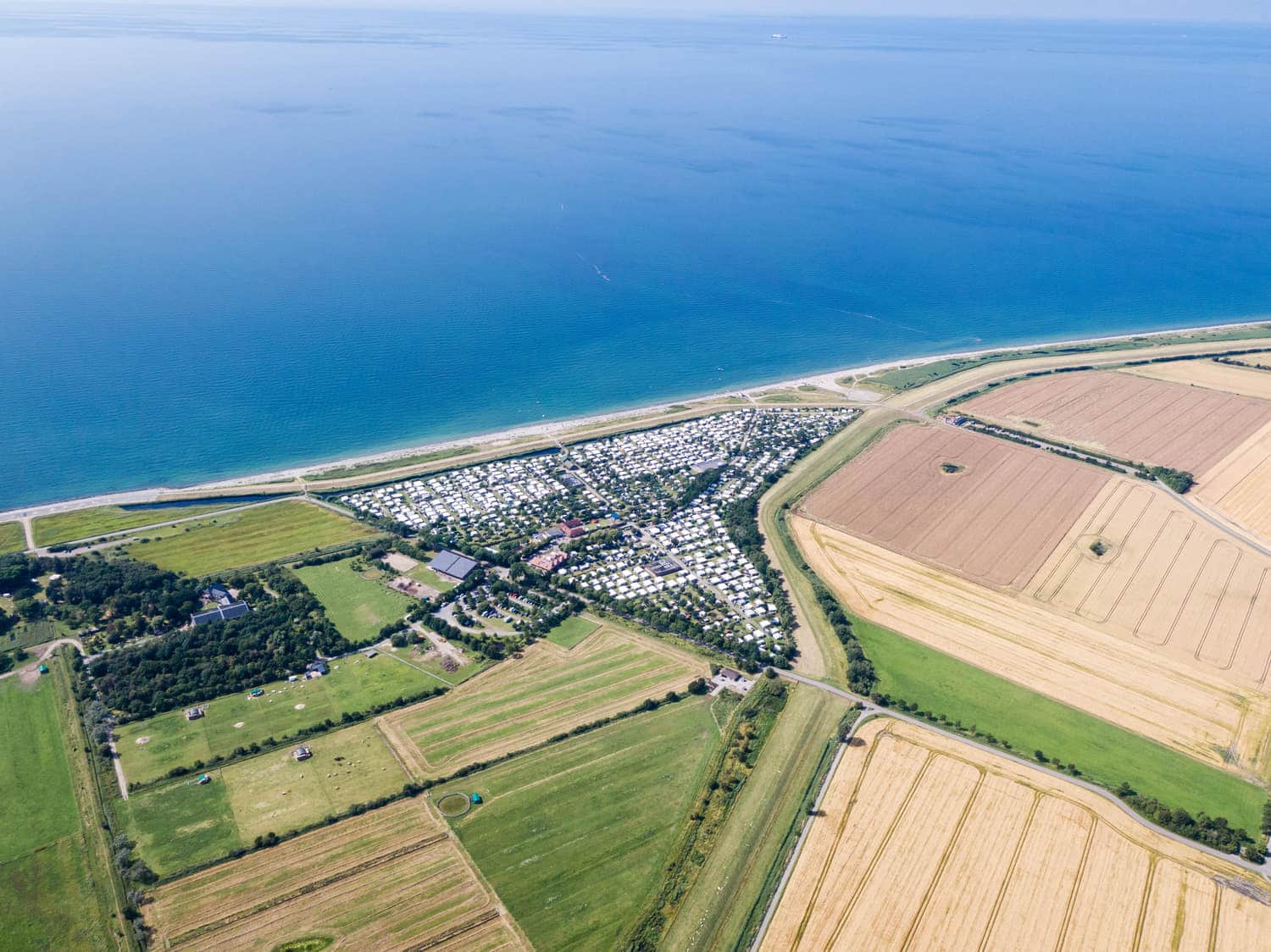 Luftbild von Feldern, Platz und Küste im Sommer