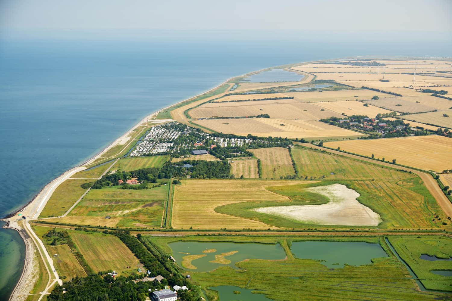 Luftbild der Felder und Teiche hinter dem Deich