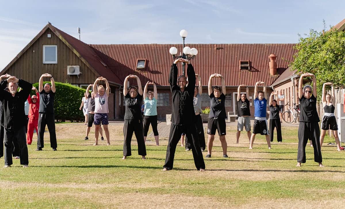Groep doet qigong op de feestweide voor het hoofdgebouw