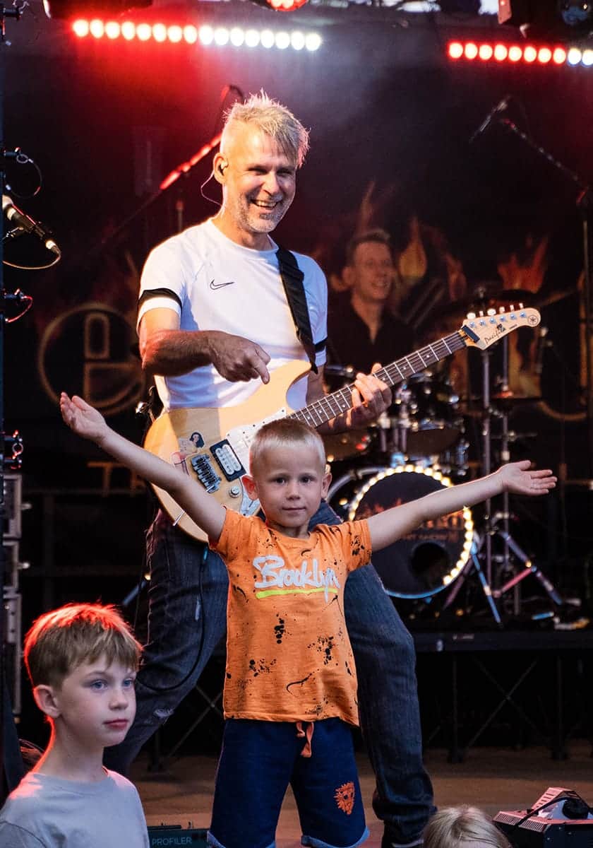 Gitarist van de liveband met een kind op het podium