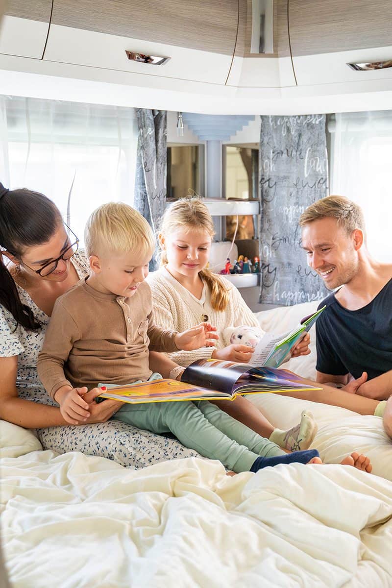 Famille assise devant une caravane de location avec auvent fixe
