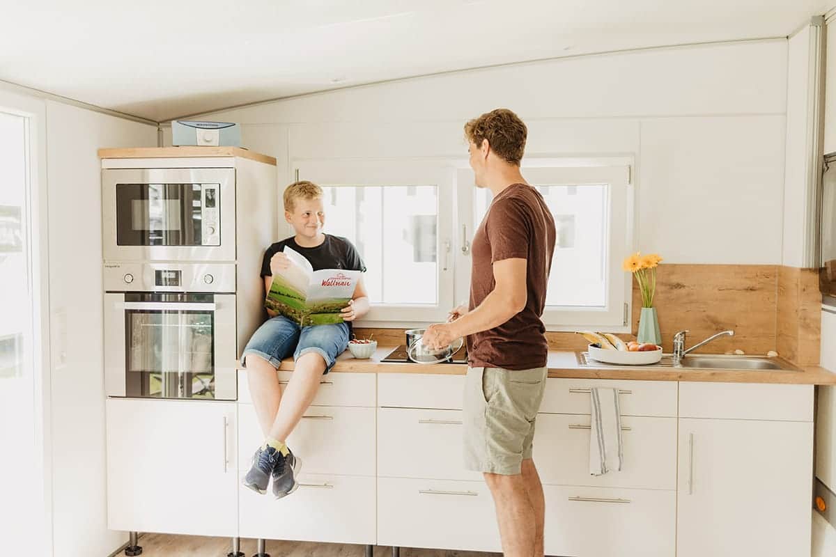 Père et fils dans la cuisine intégrée d'une caravane de location