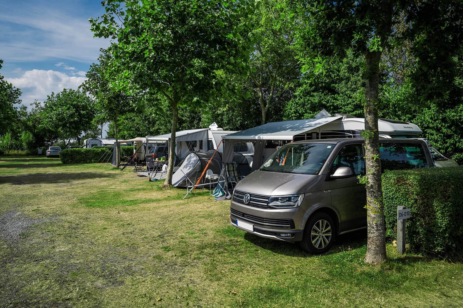 Caravan with an awning on a hedged pitch surrounded by greenery
