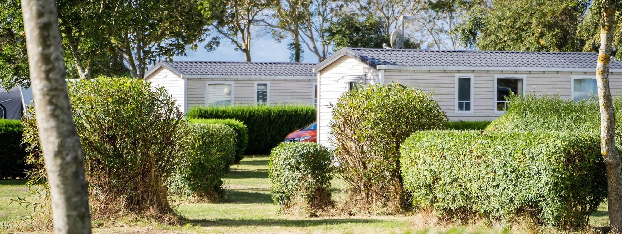 Mobilheime hinter geschnittenen Hecken auf dem Campingplatz