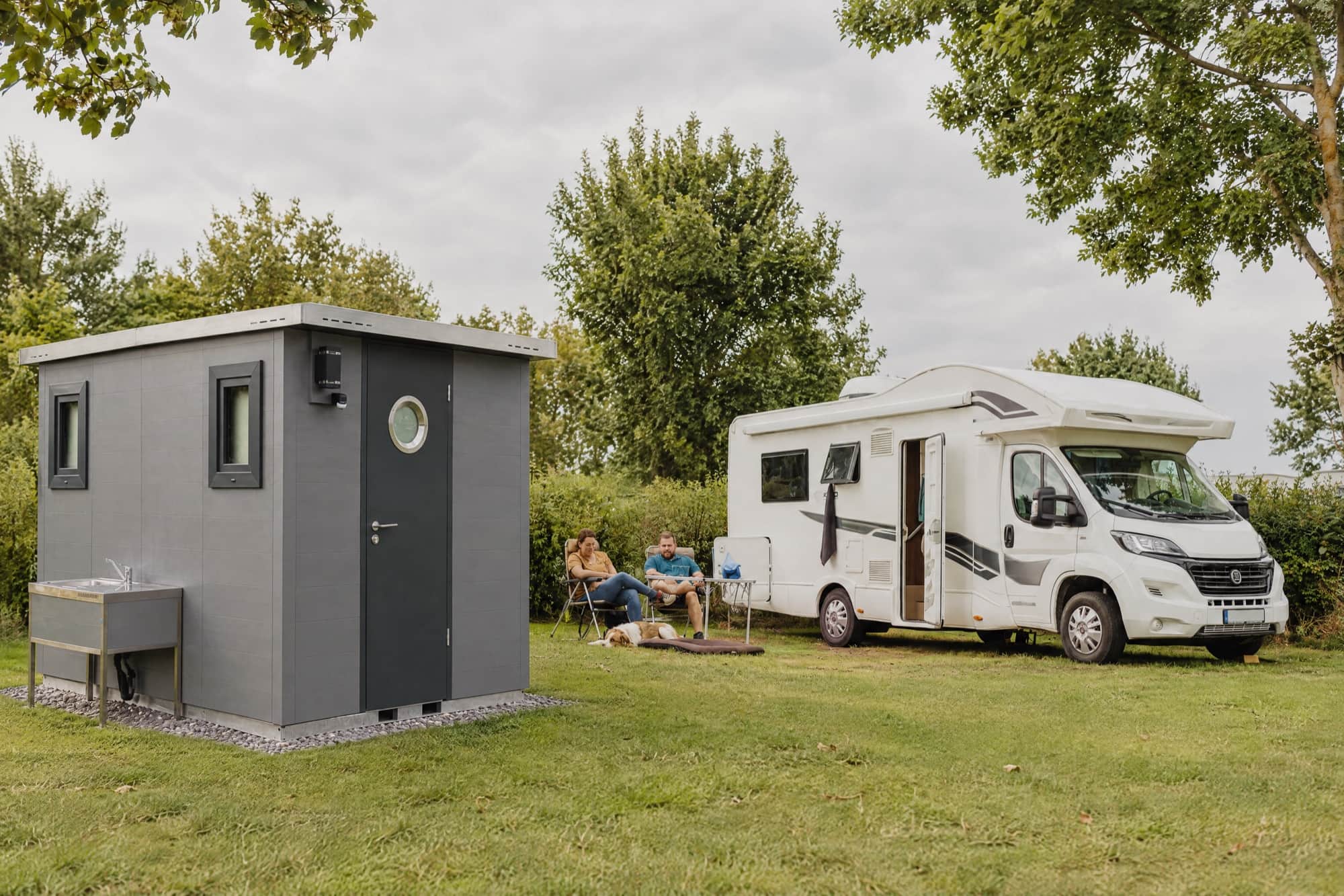 Pitch with a motorhome and its own grey sanitary cabin on the grass